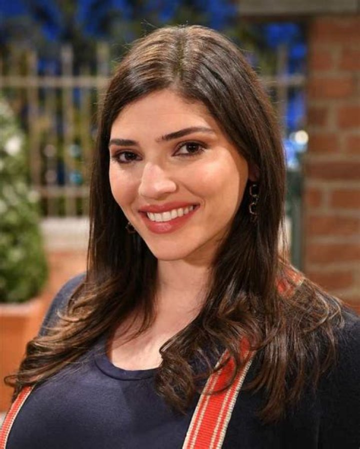Amanda Setton smiling in front of a white background, smiling