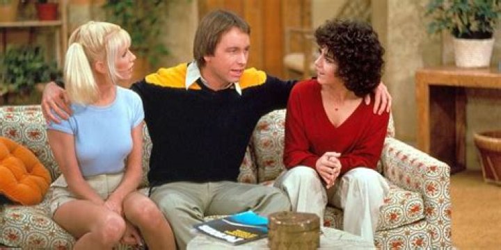 Jack, Chrissy, and Janet sitting on a couch in 'Three's Company'