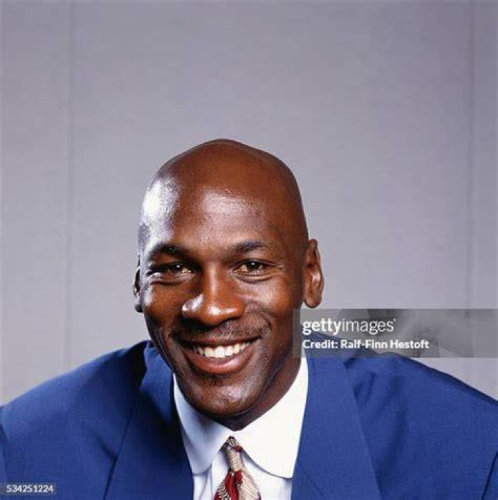 Michael Jordan smiling in front of a blue and white background